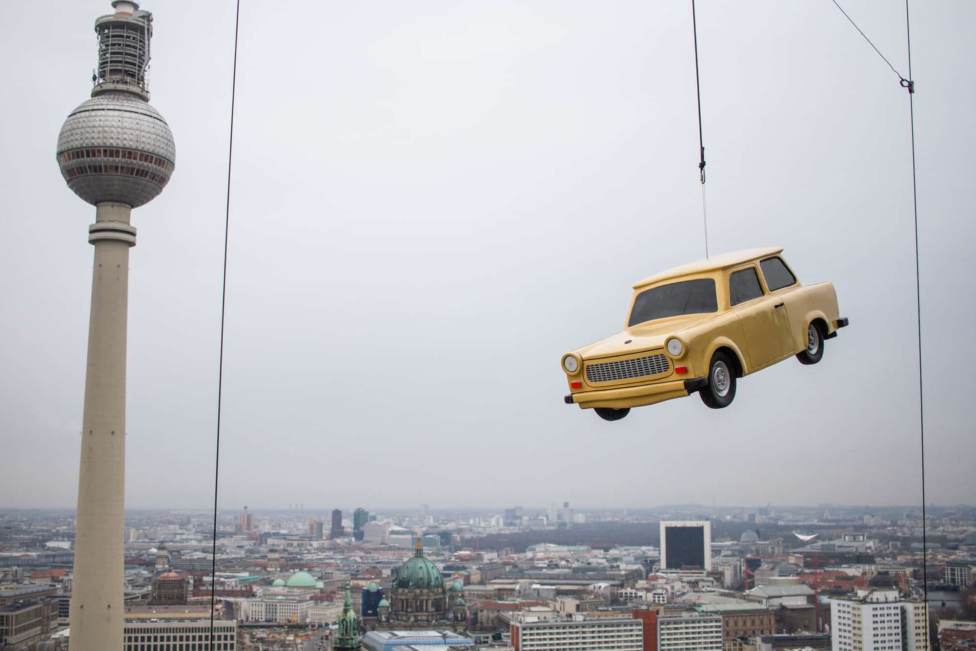 Trabi Auto hängt über der Skyline Berlins in der Luft am Base Flyer